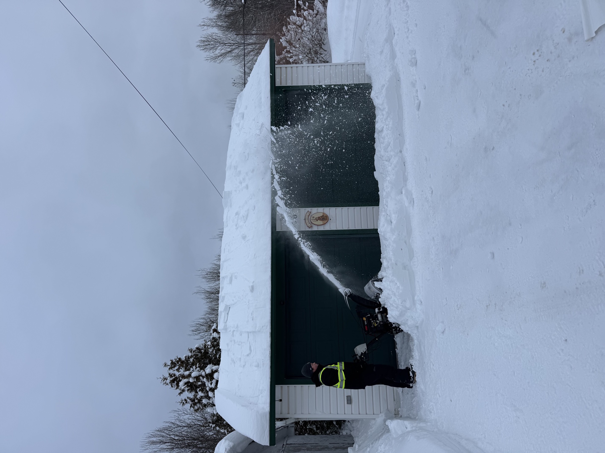 Mechanical roof snow removal in action, clearing a garage roof
