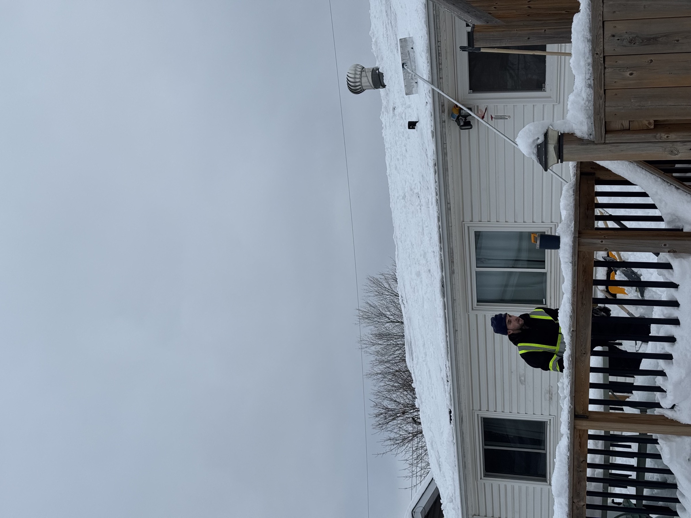 Crew member clearing a heavy snow drift beside a building