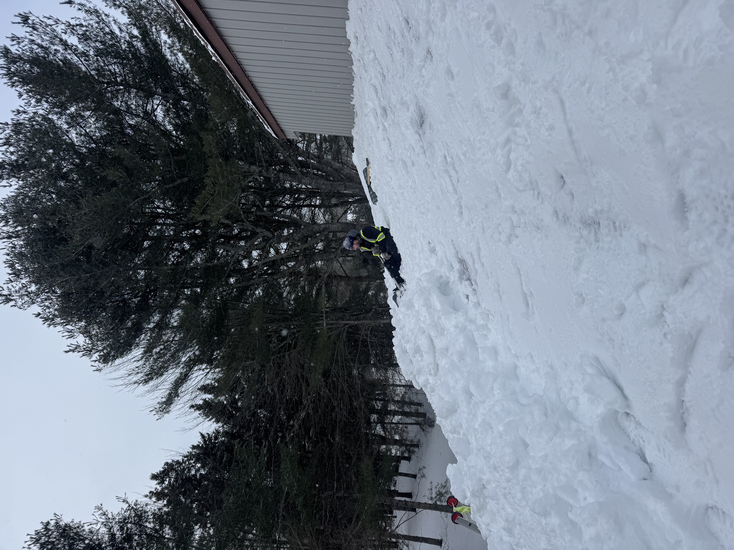 Crew member clearing snow near a roof vent from a second-storey deck