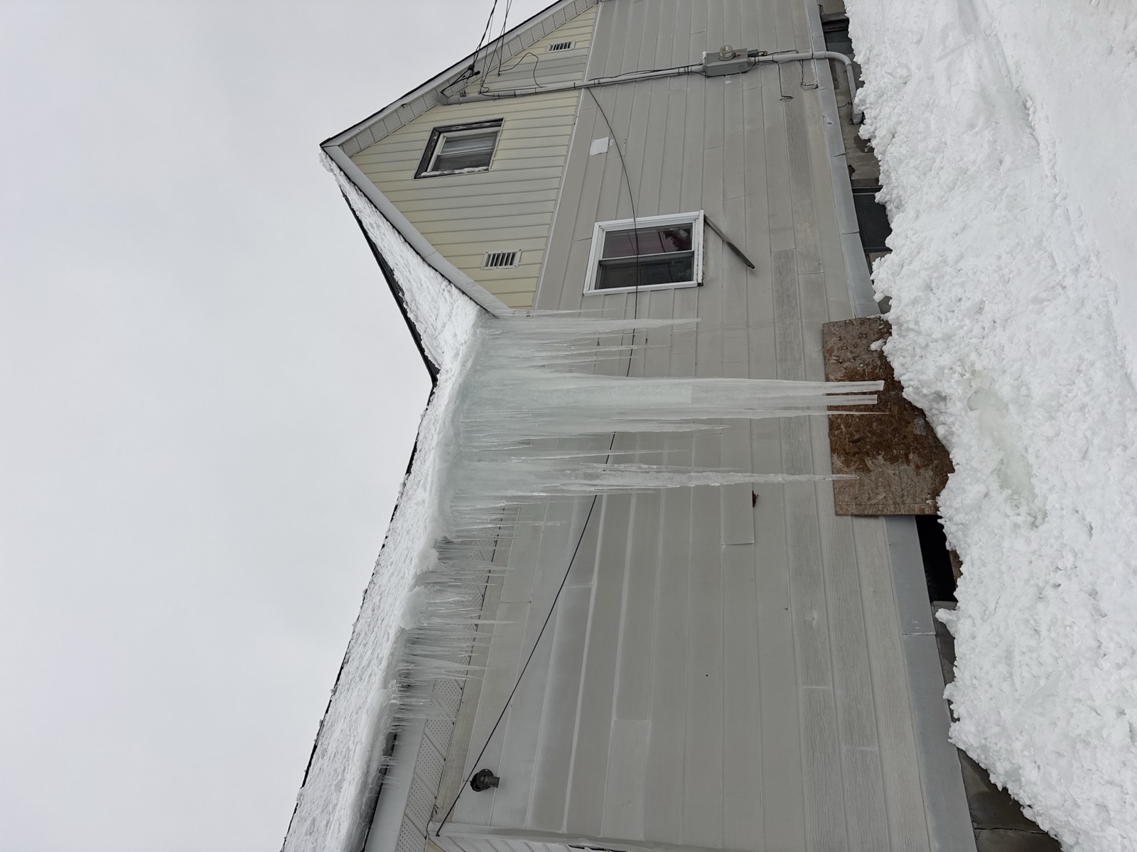 Large icicles hanging from a roofline, a sign of ice damming on a Sault Ste. Marie home